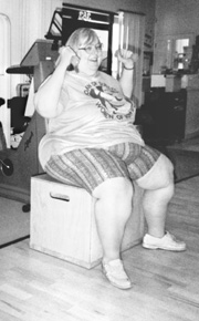 Photo of a large woman lifting hand weights while sitting on a chair